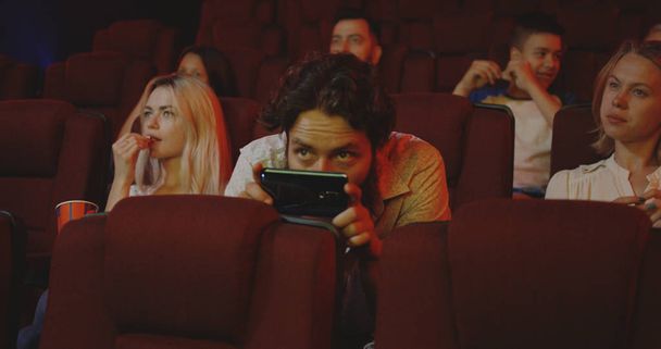 Man pirating movie with smartphone in cinema - Photo, Image