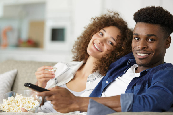 couple relaxing on the sofa eating popcorn and watching television - Photo, Image