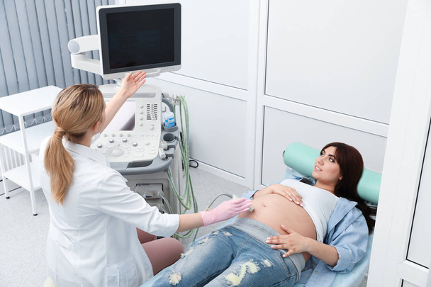 Mladá těhotná žena podrobena ultrazvukovém scanu v moderní klinice - Fotografie, Obrázek