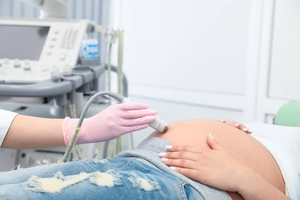 Young pregnant woman undergoing ultrasound scan in modern clinic - Fotoğraf, Görsel