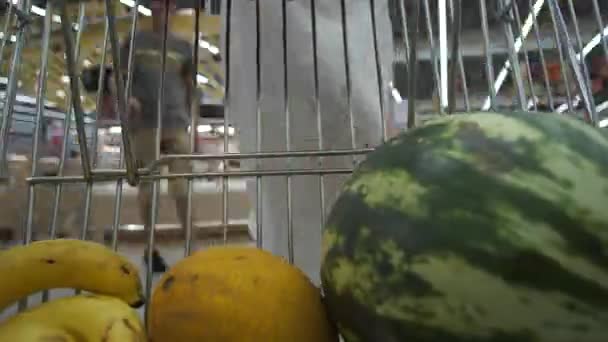 Mujer poniendo frutas en carrito de la compra en el mercado
 - Metraje, vídeo