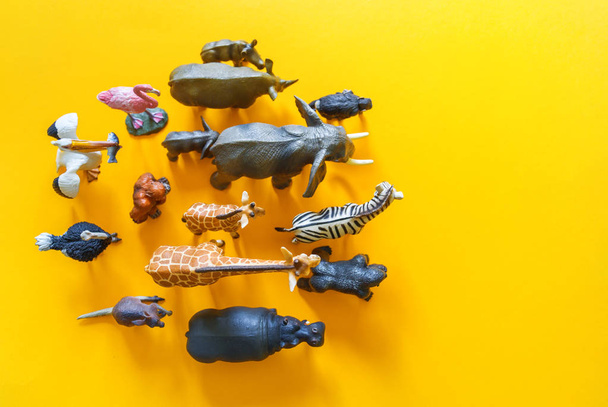 African animals in plastic. The figure of a mammal is tangled in the package. Yellow background. - Photo, Image