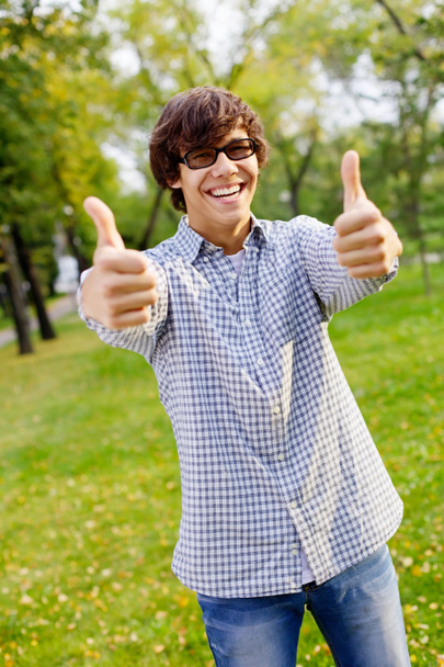 Happy guy showing thumbs up in park - Foto, imagen