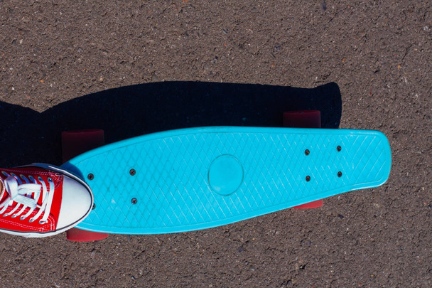 Close up of feet and blue penny skate board with pink wheels. - Фото, изображение