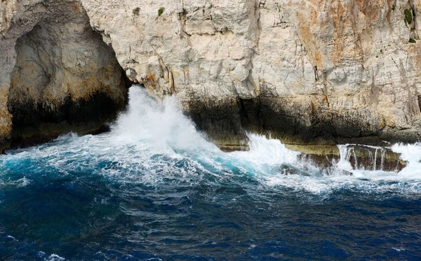 Wave breaking on the rocks in the sea,nice Blue Grotto view in Malta island close up, rock and water, Blue Grotto, view to the rock from the sea, popular,nice place in Malta,crystal sea water, nature - Photo, Image