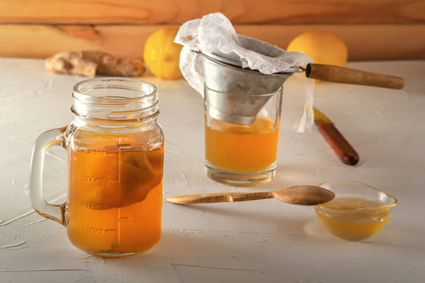 hausgemachtes fermentiertes Getränk Kombucha im Glas mit Zitrone, Honig und Ingwer auf einem Holztisch. - Foto, Bild