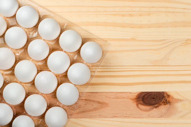 Много белых куриных яиц в лотке. Фоновое пространство Wood Pinus для текста
. - Фото, изображение