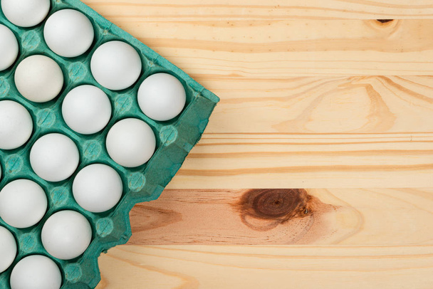 Many white chicken eggs in tray box. Wood Pinus background space for text. - Photo, Image