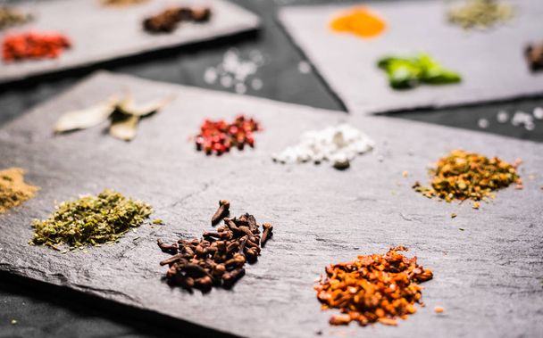 Large selection of different colorful contrast spices and seeds on slate - Photo, Image