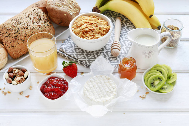 Café da manhã saudável: tigela de flocos de milho, jarro de leite, frutas fatiadas
 - Foto, Imagem