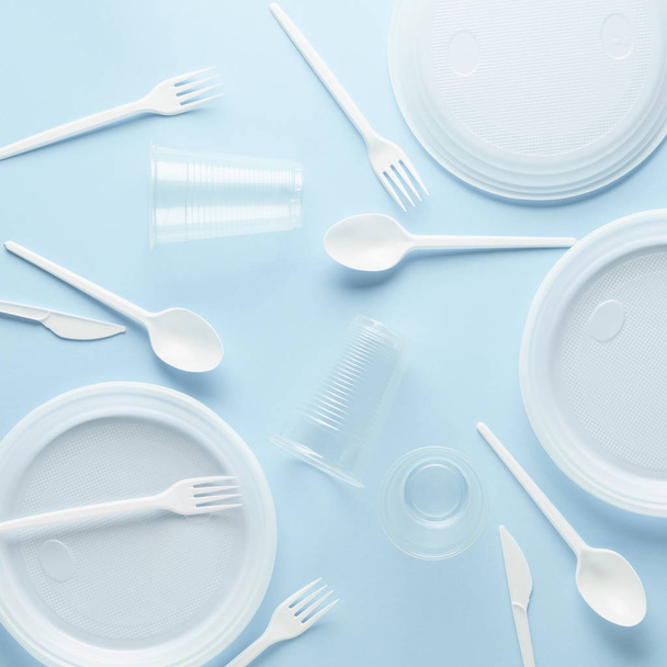 Various white plastic disposable tableware on blue background. - 写真・画像