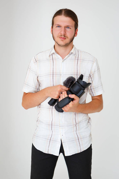 Portrait of serious young man videographer with whiskers holding professional movie camera.  - Fotoğraf, Görsel