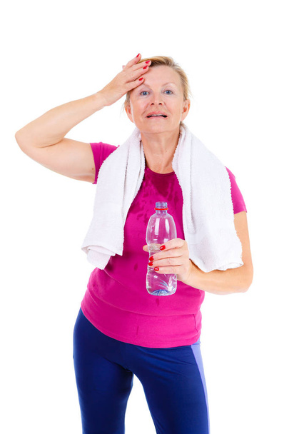 Smile Senior old woman with white teeth wiping off sweat off her forehead and holding a bottle of water in hand, isolated on white background, Positive human emotions - Photo, Image