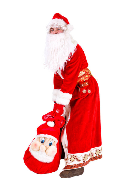 Der traurige Weihnachtsmann steht auf dem Boden und hält die Tüte mit den Geschenken. isoliert auf weißem Hintergrund. Weihnachtskonzept - Foto, Bild