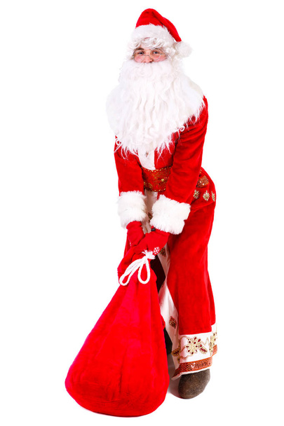 Der traurige Weihnachtsmann steht auf dem Boden und hält die Tüte mit den Geschenken. isoliert auf weißem Hintergrund. Weihnachtskonzept - Foto, Bild