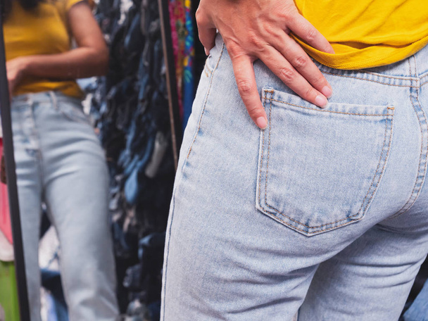 Gros plan derrière le dos d'une femme asiatique essayant de magasiner des jeans
 - Photo, image