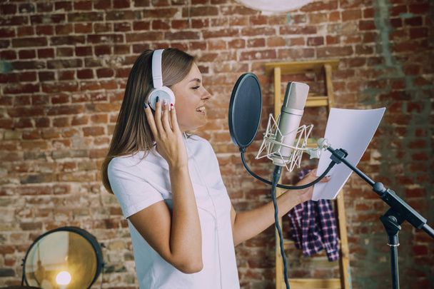 Woman recording music, broadcasting and singing at home - Foto, Imagen