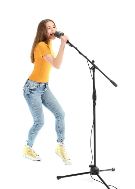 Έφηβο κορίτσι με μικρόφωνο που τραγουδά ενάντια στο λευκό φόντο - Φωτογραφία, εικόνα