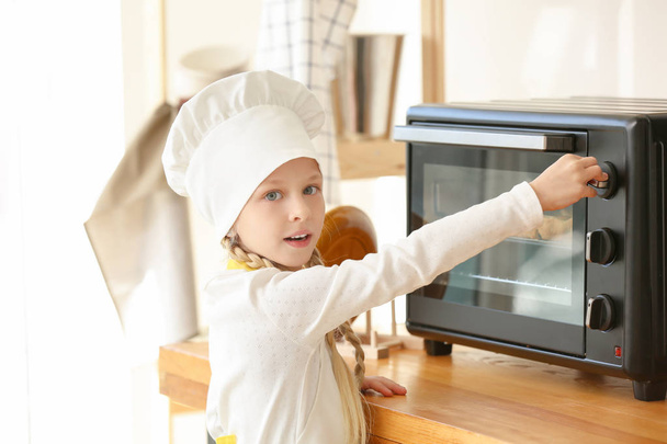 Cute little chef cooking in kitchen - Foto, afbeelding