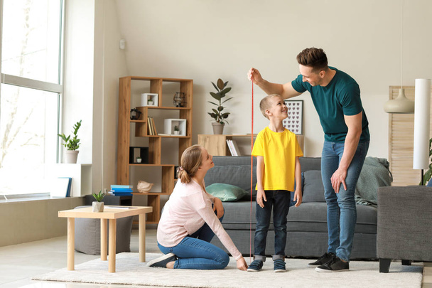 Padres midiendo la altura de su hijo en casa
 - Foto, imagen