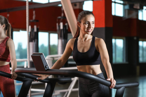 Sporty young woman on treadmill in gym - Foto, imagen