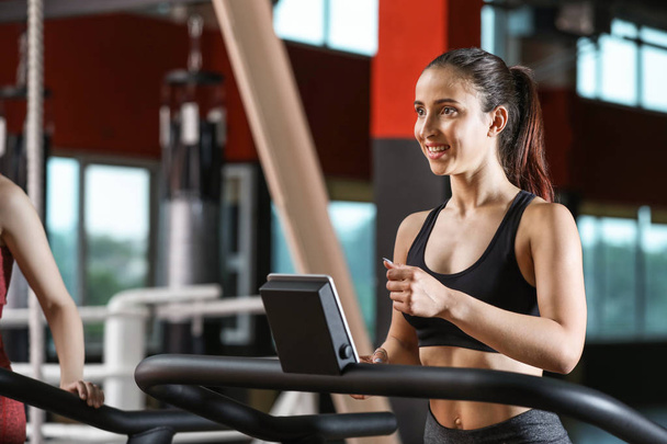 Sporty young woman on treadmill in gym - Foto, Imagen