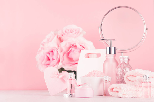 Different skin care products with romantic roses bouquet, round mirror on girlish elegant pink pastel background. - Foto, immagini