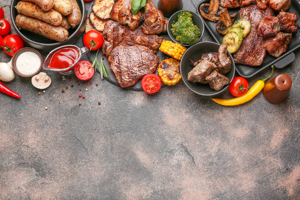Вкусное мясо на гриле с сосисками и овощами на сером фоне
 - Фото, изображение