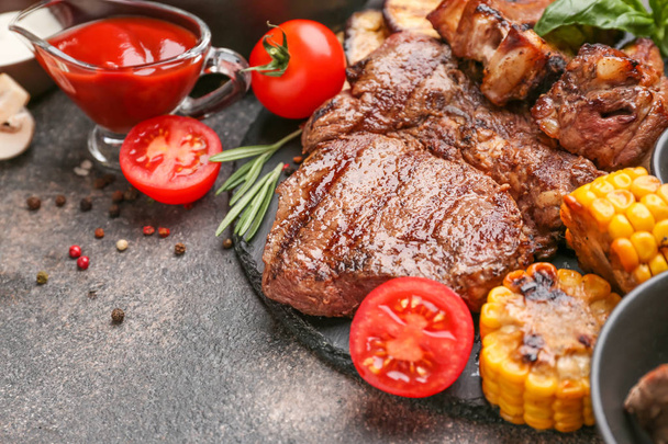 Maukasta grillattua lihaa ja vihanneksia pöydällä
 - Valokuva, kuva