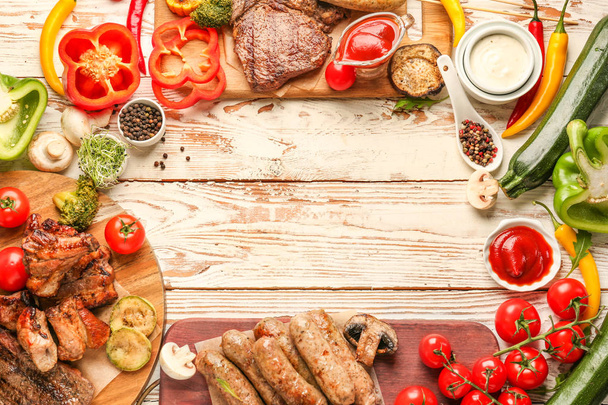 Frame made of tasty grilled meat with sausages and vegetables on wooden background - Photo, image