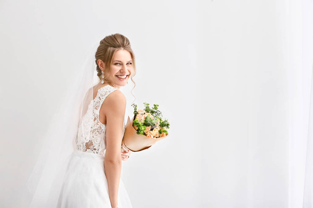 Hermosa joven novia con ramo de flores sobre fondo blanco
 - Foto, imagen