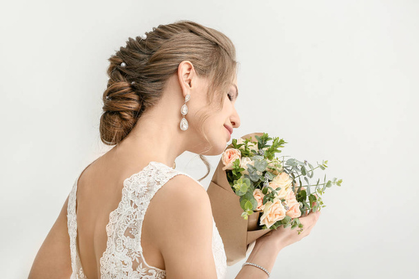 Beautiful young bride with bouquet of flowers on white background - Photo, Image