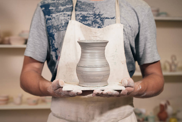 Young man holding clay vase. Creating pottery. Craftsman with ce - Photo, Image