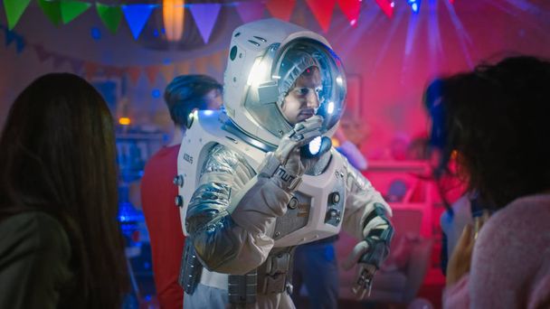 At the College House Costume Party: Fun Guy Wearing Space Suit Dances Off, Doing Robot Dance Modern Moves. With Him Beautiful Girls and Boys Dancing in Neon Lights. - Foto, Bild