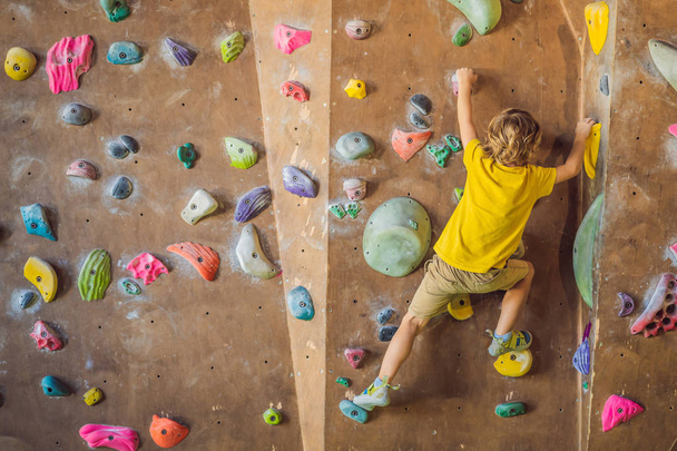 little boy climbing a rock wall in special boots. indoor - Foto, Imagem