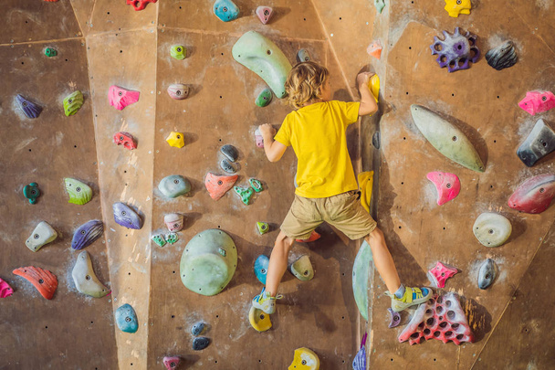 little boy climbing a rock wall in special boots. indoor - Photo, Image