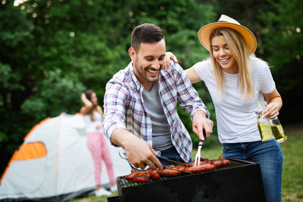 Happy friends making barbecue and having lunch in the nature - 写真・画像