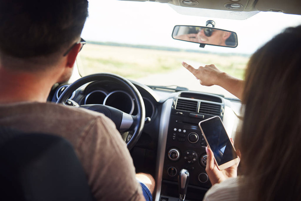 Casal jovem usando um telefone celular durante a viagem de carro
  - Foto, Imagem