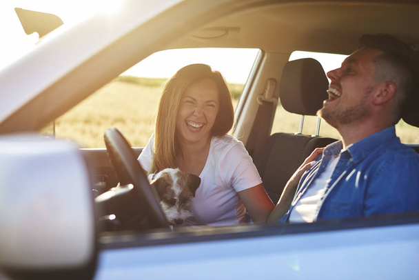 Escena alegre de pareja joven y perro durante el viaje por carretera
  - Foto, imagen
