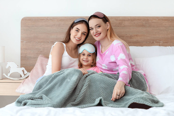 Happy lesbian couple with little daughter in bedroom - Photo, Image