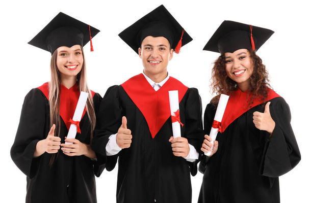 Mladí studenti na bakalářských hábitech s palcem na bílém pozadí - Fotografie, Obrázek