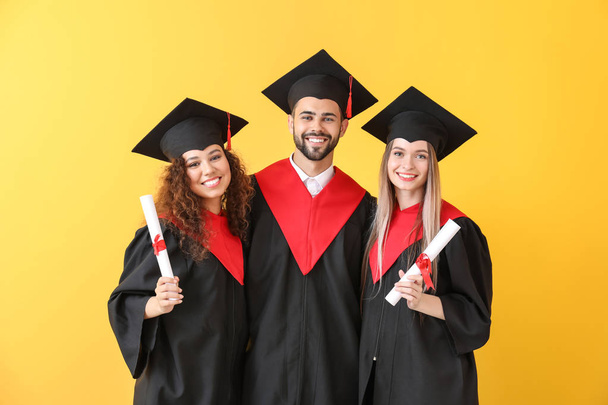 Young students in bachelor robes on color background - Photo, Image