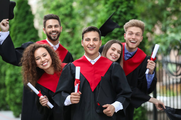 Happy students in bachelor robes outdoors - Foto, Bild