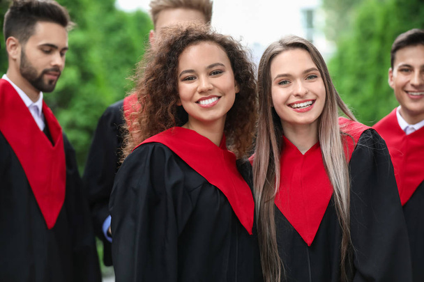 Happy students in bachelor robes outdoors - Foto, Bild