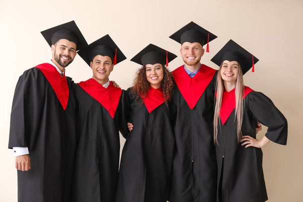 Молодые студенты в бакалаврских халатах на светлом фоне
 - Фото, изображение