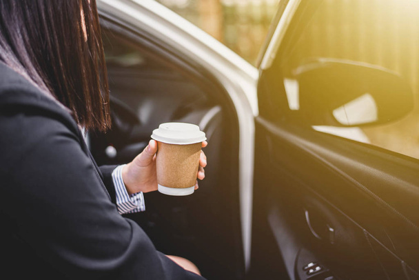 Business woman's hand holding a coffee cup to take away, she is driving in the morning. - Photo, Image