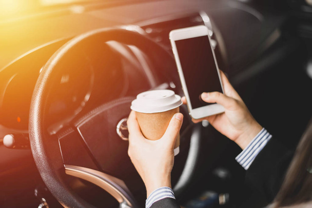 Femme d'affaires Au milieu des embouteillages donc ramasser une tasse de café dégradé à boire et regarder les plans sur le smartphone
 - Photo, image