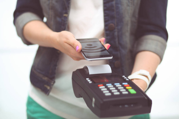 Klient płaci smartphone w sklepie przy użyciu technologii Nfc. Technologii NFC. Klient płaci. - Zdjęcie, obraz
