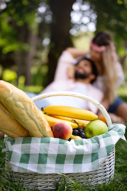 Happy young couple enjoying picnic in park outdoor - Foto, imagen