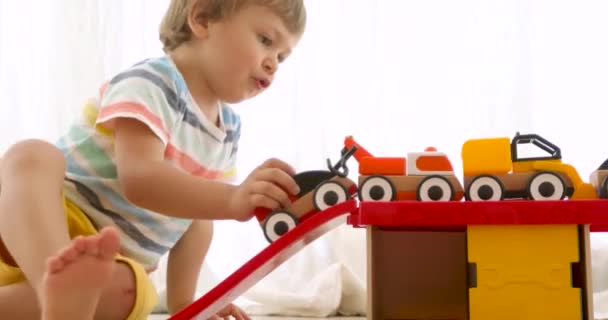 Three years old child boy play with wooden toy cars - Filmagem, Vídeo